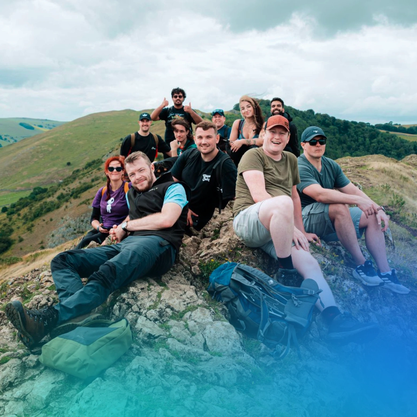 Team sitting at the top of a mountain looking happy