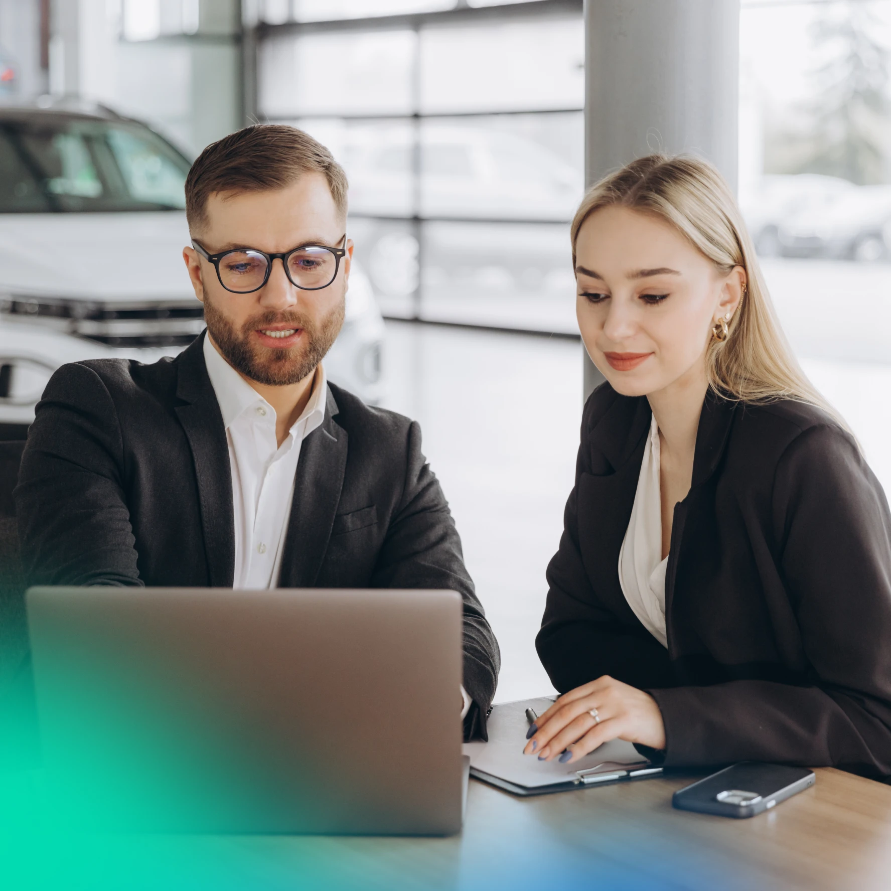 Man and woman on a laptop in a car dealership