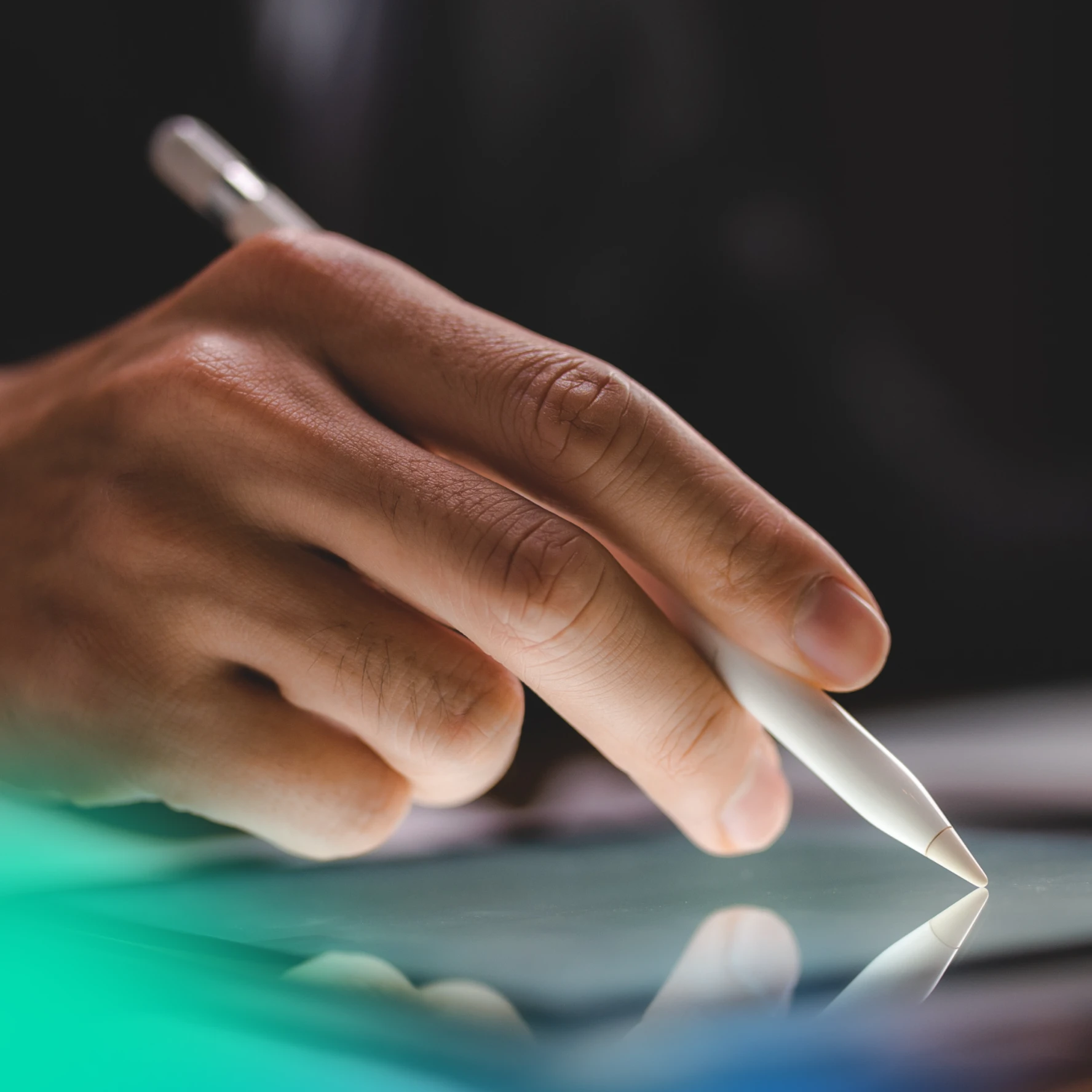 hand holding a pencil to a tablet