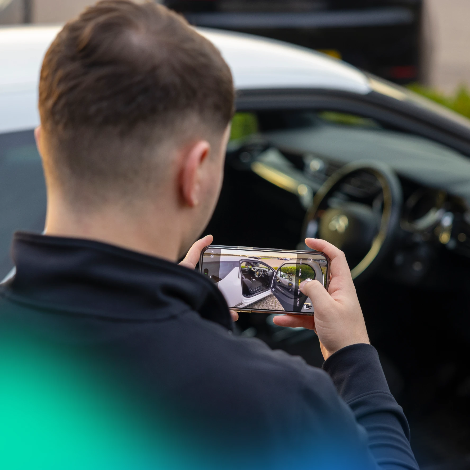 A man taking pictures of his car on his phone