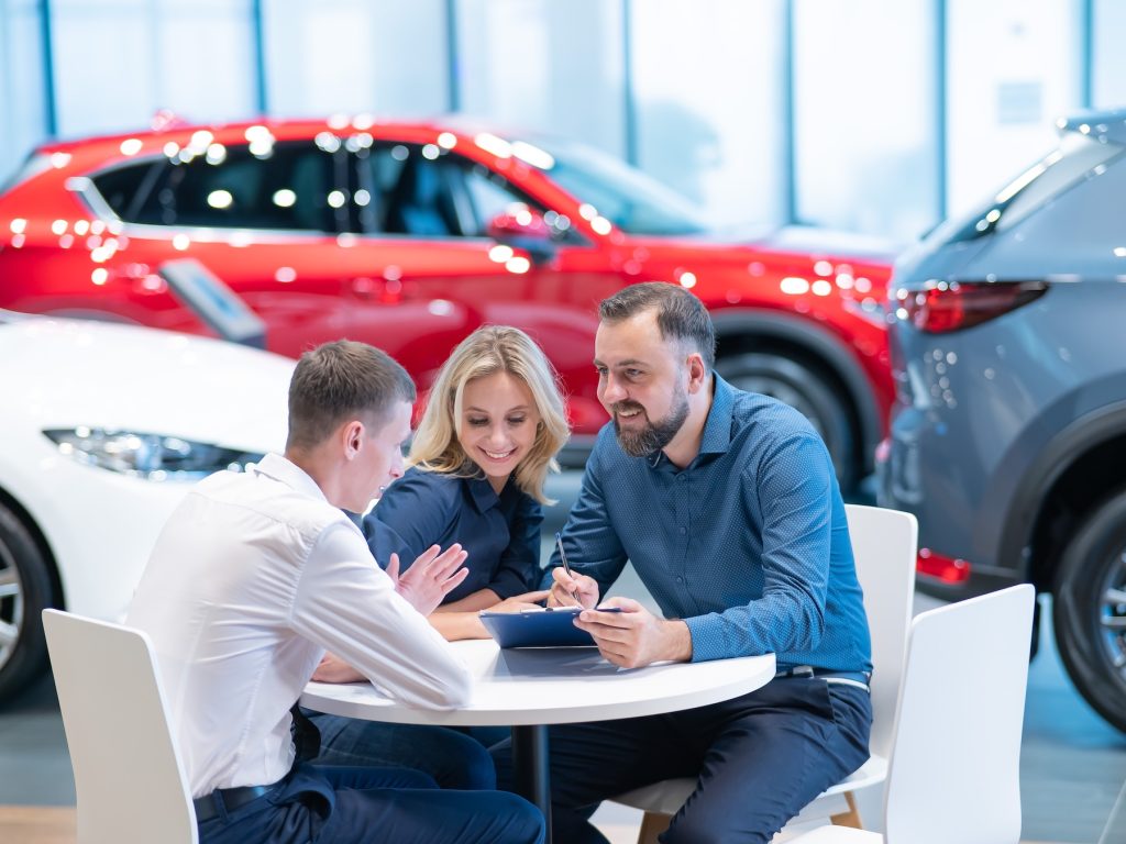 Couple buying a car and reviewing financial agreement